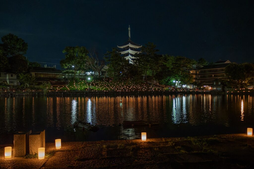 Candles at the Sarusawa Pond venue of Nara Tokae with Kofuku-ji pagoda behind