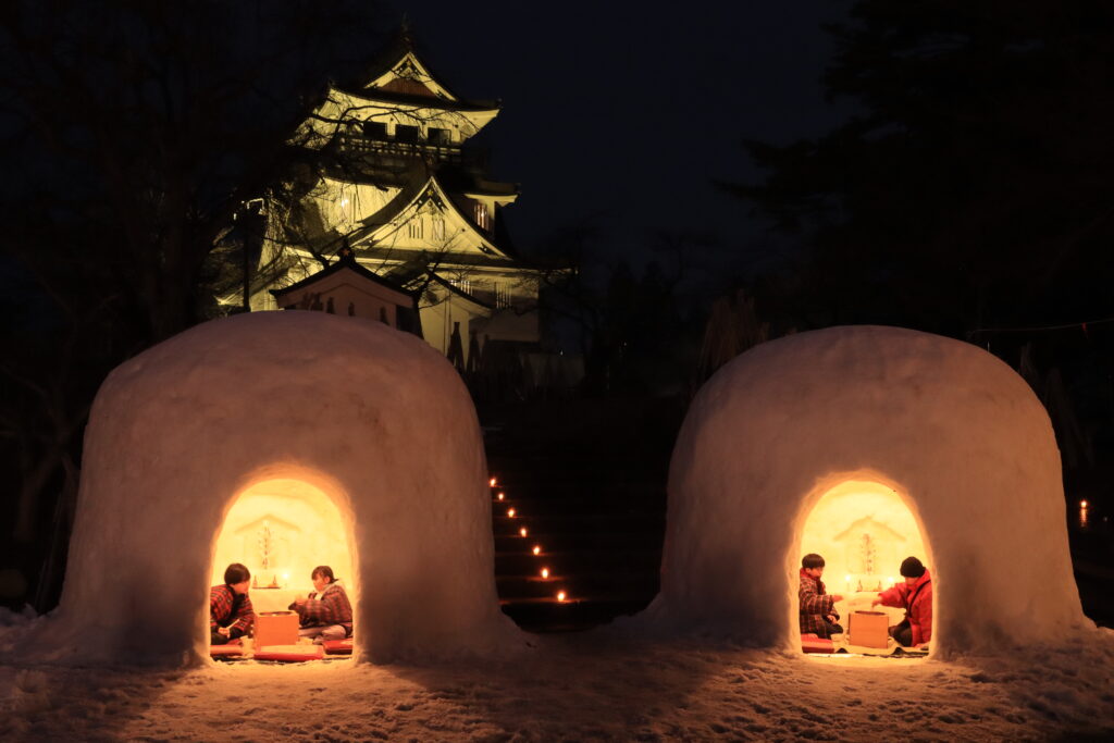 Kamakura snow huts lit by candles at Yokote Castle, Akita